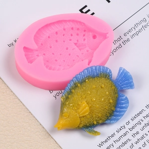 Detail view showing a pink silicone fish mold with a yellow and blue clay fish model