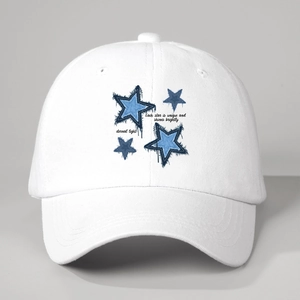 Detail of blue denim star patches with frayed edges on a white cotton baseball cap
