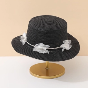 Detailed macro view of black woven straw boater hat with handmade white gauze flowers