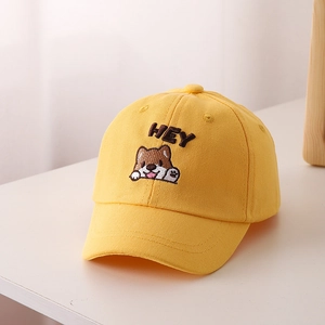 Dettaglio di un cappello da baseball giallo in cotone con ricamo cucciolo e testo HEY