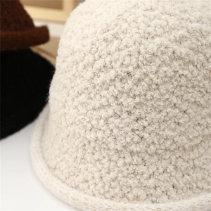 Close-up of beige knit bucket hat showing plush sherpa texture and woven edge details