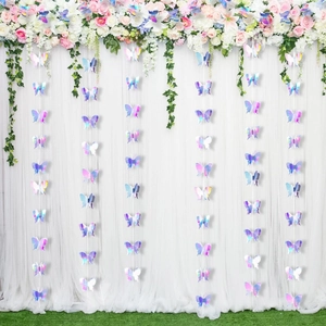 Close-up of iridescent laser cut butterfly garlands hanging on a white wedding backdrop