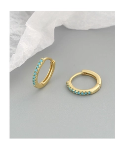 Detail of gold huggie earrings with turquoise stones and S925 hallmark on a gray background