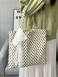 Detail view of large canvas tote bag featuring retro polka dots and a lace bow accent