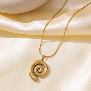 Golden stainless steel spiral pendant necklace on silk fabric with elegant pebble accent