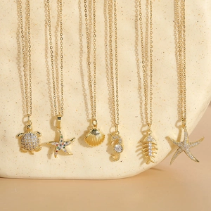 Detailed display of six ocean-themed gold pendants with zircons on textured stone props