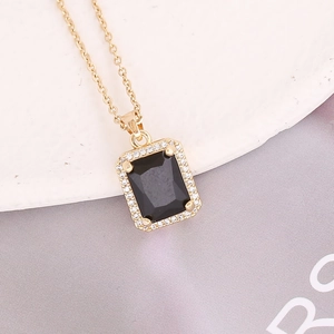 Detailed close-up of a square black pendant with white zircons on a gold chain necklace