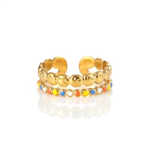 Detail of adjustable gold ring featuring stacked layers with smiley face and colorful enamel beads