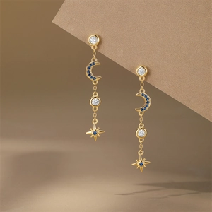 Detail of star and moon dangle earrings with blue crystals and long gold chain
