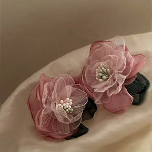 Detailed close-up of pink layered fabric floral earrings with delicate petals and leaves
