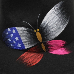 Detailed view of hand-painted butterfly with US flag wing on black felt fedora hat