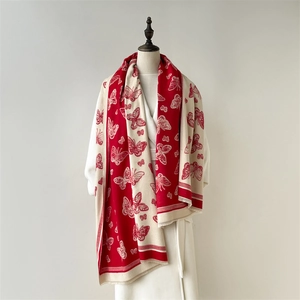 Detailed view of red and beige cashmere scarf with elegant butterfly prints and fringes