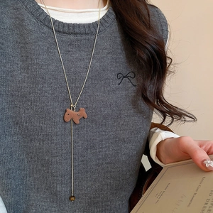 Detailed view of long gold necklace featuring a brown dog pendant and tiger eye bead