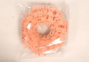 Detail of pink Christmas wreath with maple leaves inside clear plastic packaging
