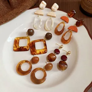 French vintage resin earrings set with amber and marble patterns on a ceramic plate