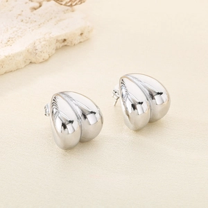 Détails macro des boucles d'oreilles cœur en forme de C argenté avec fini poli miroir