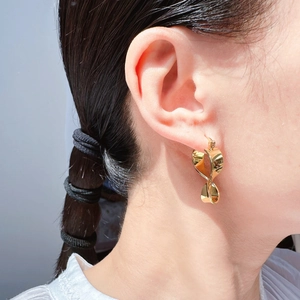 Modern minimalist twisted geometric gold earrings with polished metallic luster on model