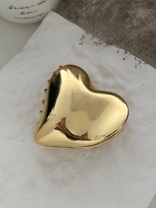 Detailed view of elegant gold heart hair claw clip on white textured stone surface