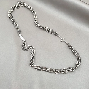 Close-up of layered silver chain necklace with rectangular tag and cross star pendants