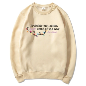 Beige Christmas hoodie with festive lights and humor quote on a white background