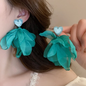 Close-up of green fabric flower tassel earrings with heart studs on model
