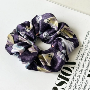 Detail of purple satin scrunchie featuring cute ghost and spider web Halloween patterns