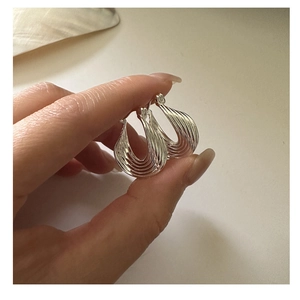Detailopname van S925 sterling zilveren oorringen met golvende lagen en gebogen afwerking