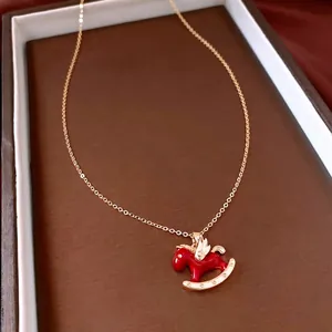 Goldene Kette mit rotem Pony-Anhänger präsentiert in einer braunen Leder-Schmuckschatulle