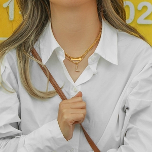 Detailed macro of gold-plated double-layer necklace with a sparkling letter L pendant