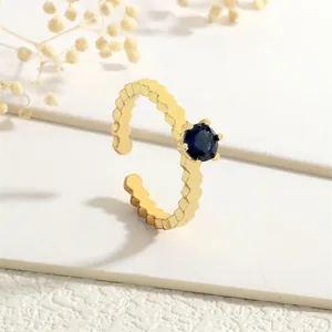 Detail of 18K gold wave band ring featuring a prong-set round blue zircon stone