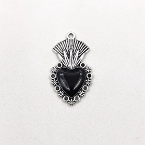 Detailed shot of a vintage gothic silver heart pendant with black center gem and floral motifs