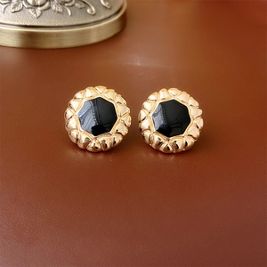 Macro detail of vintage gold round earrings with black center and wavy texture