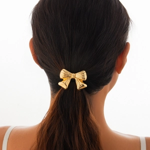 Detail of a golden alloy bow hair tie shown on a high ponytail for a sleek fashion look