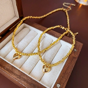 Detail shot of two gold beaded bracelets with heart pendants in a wooden jewelry box