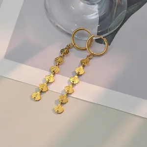 Close-up of golden drop earrings featuring shell-shaped metal sequins on a stylish background