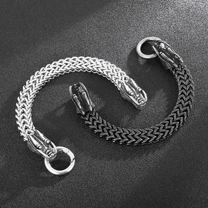Detail of silver and vintage black dragon head bracelets with woven steel chain texture