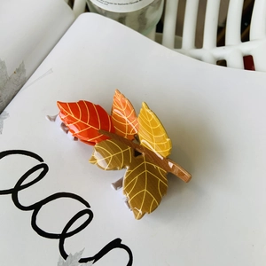 Detail of autumn maple leaf hair claw clip with vibrant red and orange acrylic texture
