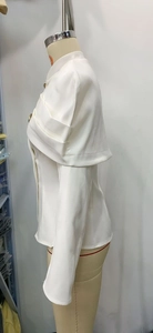 Detailed side view of elegant white blazer featuring a wide shawl collar and gold buttons