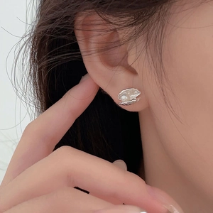 Close-up of minimalist S925 silver shell earrings with pearls worn on ear