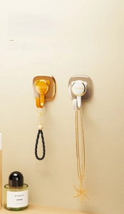 Detail of adhesive wall hooks in orange-gold and white holding keys and jewelry