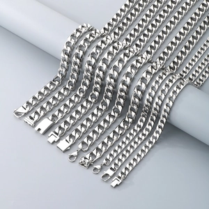 Multiple silver Cuban link necklaces in various widths on white cylinder display