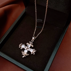 Detail view of rose gold cross pendant with white gemstones in a black jewelry box