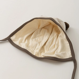 Cute newborn baby knit bonnet with pom pom and earflaps in cream and brown colors