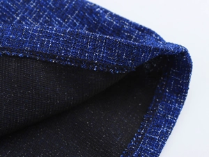 Close-up of blue tweed fabric texture with black lining on a sleeveless suit set