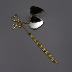 Detailed view of a golden heart-shaped mirror pendant with a long chain and bow charm