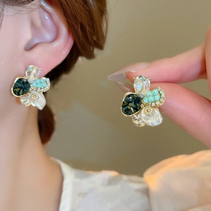 Gros plan sur les boucles d'oreilles fleuries avec pierres vertes, perles et cristaux
