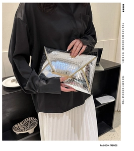 Detail of silver crocodile-embossed envelope clutch with gold metal buckle