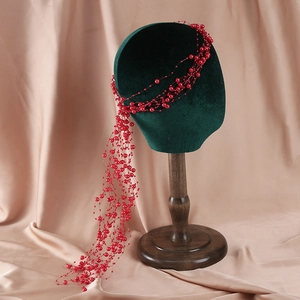 Detailed view of red beaded bridal hair band with tassels on velvet mannequin