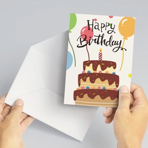 Détail d'une main tenant une carte d'anniversaire avec motif gâteau et enveloppe blanche