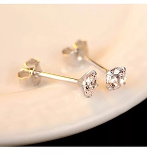 Macro shot of silver four-prong stud earrings with round white cubic zirconia stones